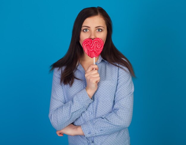 Woman is closing her mouth with a lollipop against of glue background