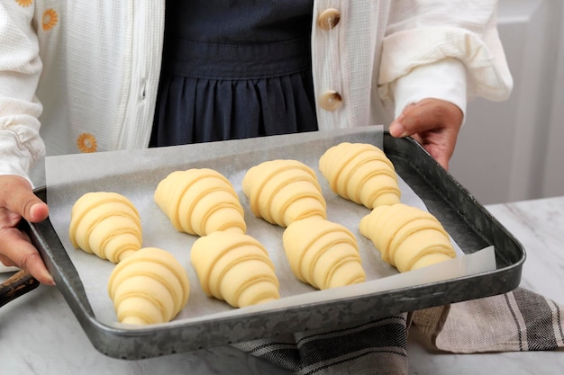 A Woman is Cooking Croissants. Prepare for Baking. Delicious Traditional French Crispy Croissants, Homemade Bakery, Cuisine for Family. Girl Chef Work on Kitchen Table. Raw Croissants