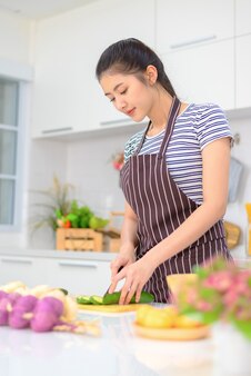 La donna sta cucinando nella cucina di casa. le mani femminili tagliano le verdure, sul tavolo. donna che impara a fare un'insalata e cibo sano, resta a casa concetto.