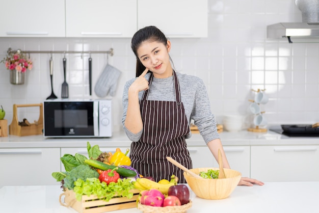 여자는 집 부엌에서 요리를 하고 있다. 샐러드와 건강에 좋은 음식을 만드는 법을 배우는 여성, 집에서 지내세요.