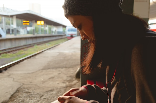 女性は駅で電車を待っている間お金を数えています。