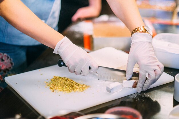 Woman is cutting nuts pistachio on the table on the white