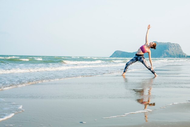 A woman is doing a yoga at the beach