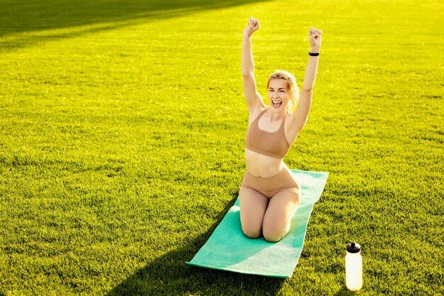 A woman is doing yoga on a green mat on a field