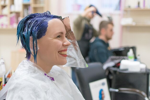 A woman is done coloring her head in blue at the hairdresser's salon Change the image of a woman