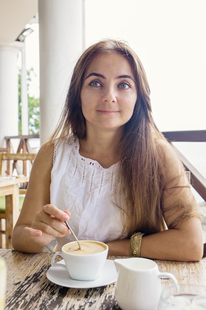 A woman is drinking cappuccino in a cafe