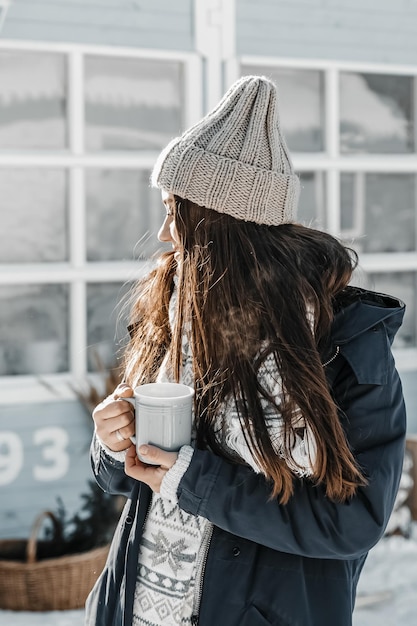 Фото Женщина пьет горячий чай на открытом воздухе возле дома зимой