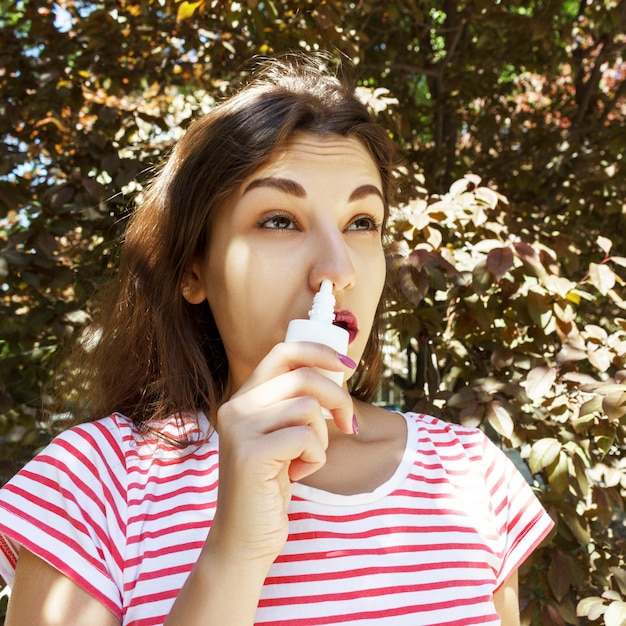 女性が鼻の詰まった鼻に点鼻薬を滴下しています。