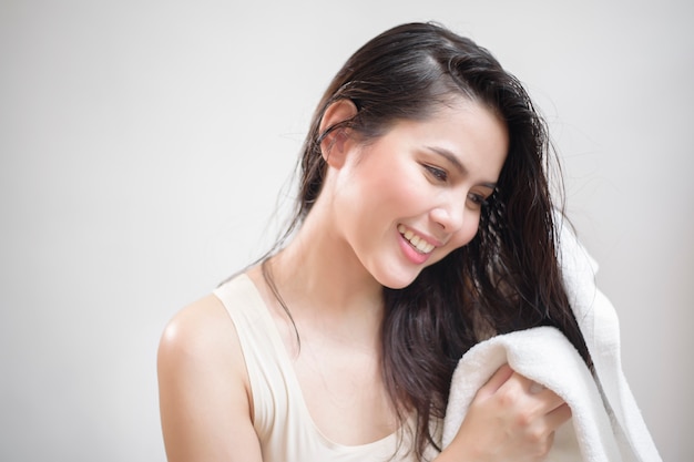 A woman is drying her hair with a towel after showering