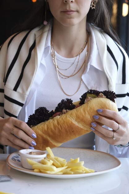 Photo a woman is eating a sandwich and a glass of wine