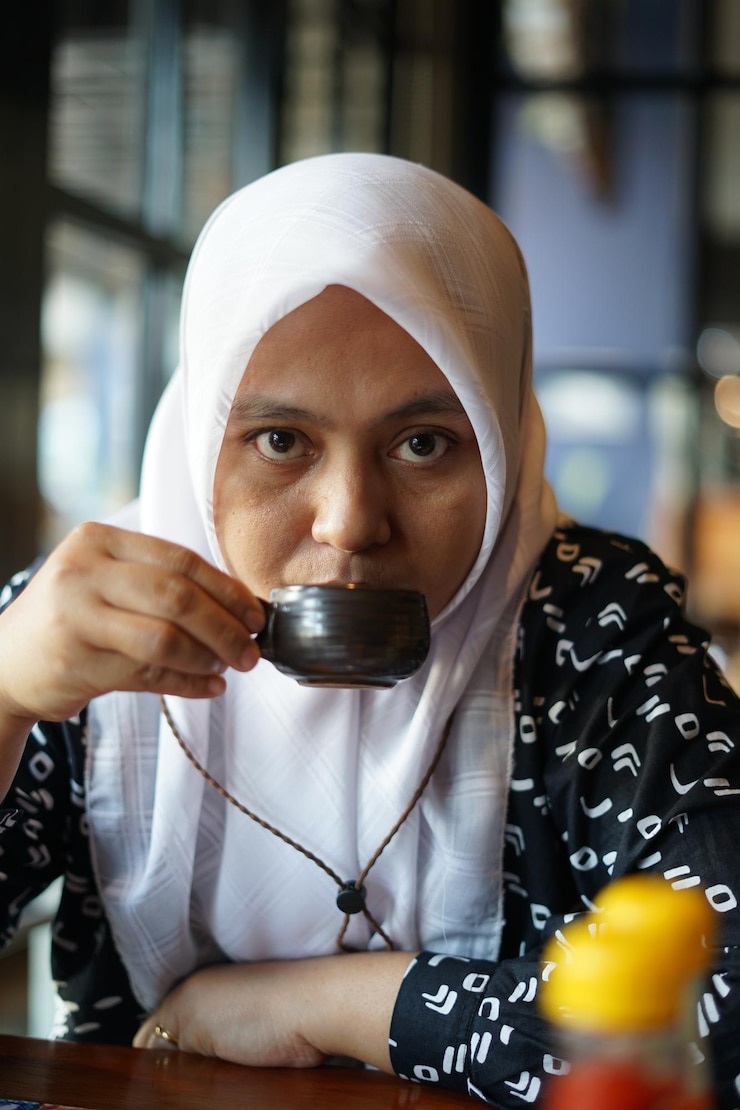 Photo 女性がカフェでお茶を楽しんでいます