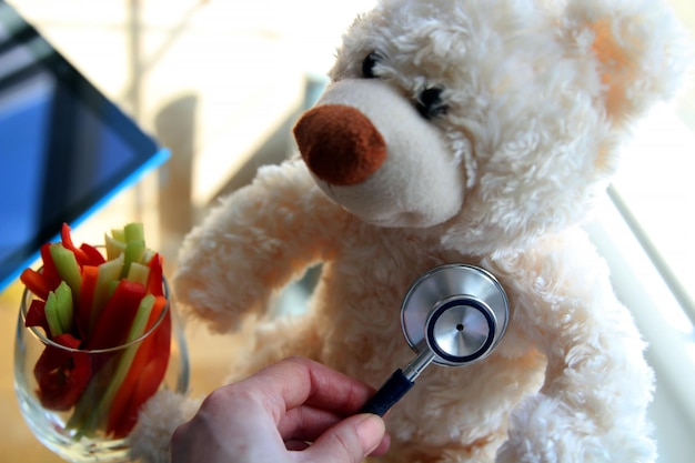 Photo woman is examining teddy bear with a stethoscope