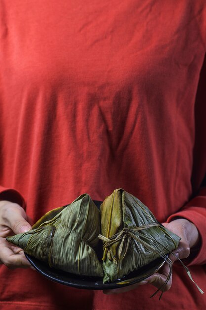 A woman is giving zongzi(rice dumpling) to others as a present on Dragon Boat Festival, 