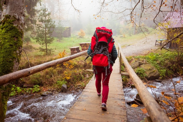 Woman is going across the wooden bridge while hiking