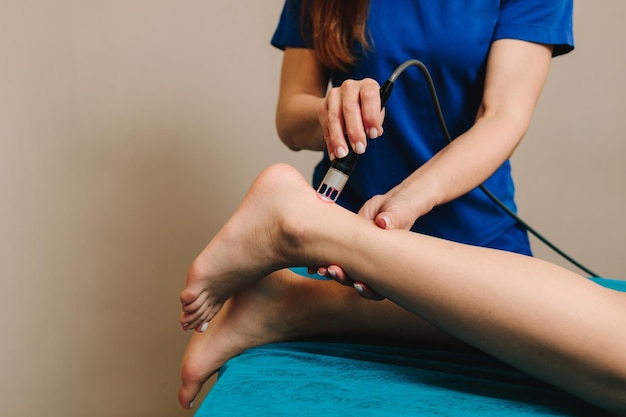 woman is going through infrared procedure to relieve painful foot conditions heal from injury and arthritis laser feet therapy to heal from chronic heel pain