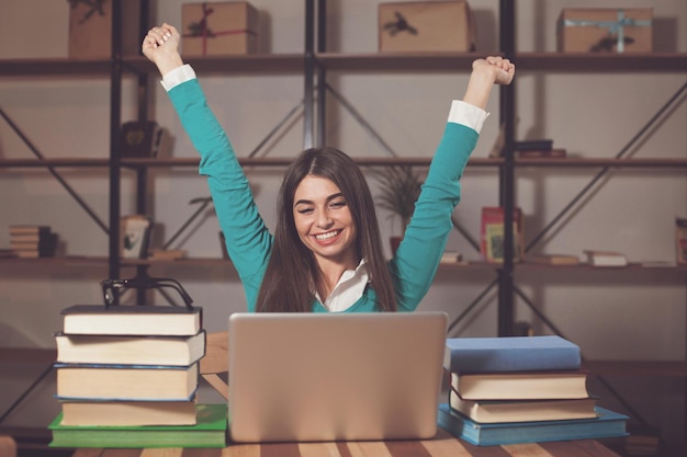 Woman is happy about her successful work with laptop at the table