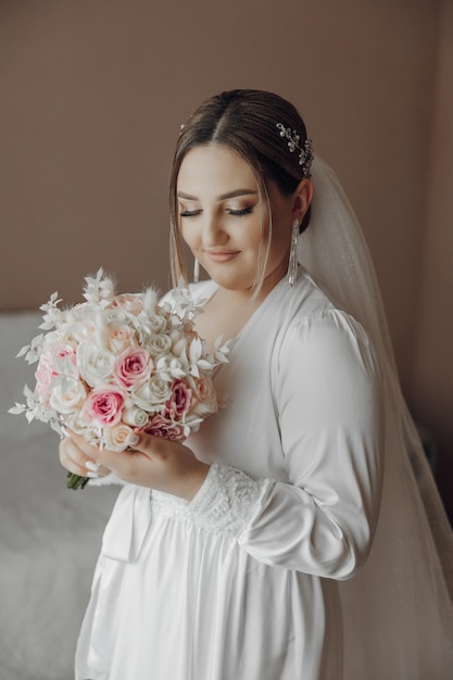 A woman is holding a bouquet of flowers and wearing a white dress