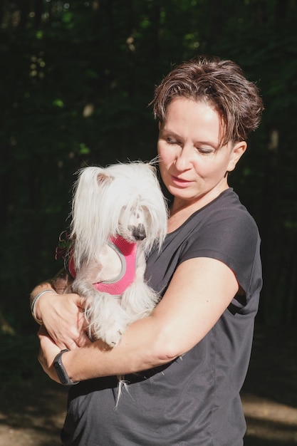그녀의 팔에 차이니즈 크레스티드 개를 안고 있는 여성