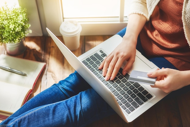 Photo woman is holding credit card and using laptop computer. online shopping concept. close up.