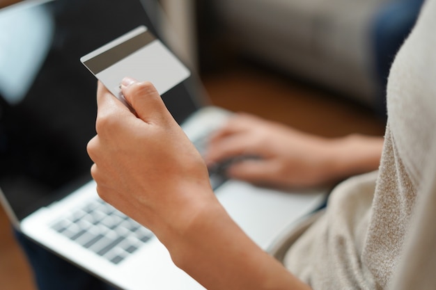 Foto la donna sta tenendo la carta di credito con il computer per lo shopping online e il pagamento