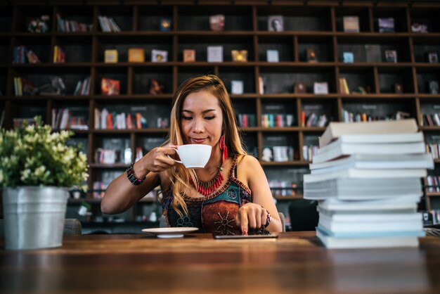  woman is holding a cup of hot cappuccino and reading a book