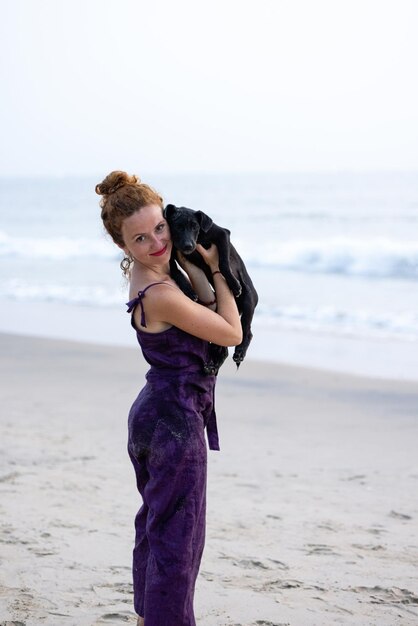 A woman is holding a dog on the beach.