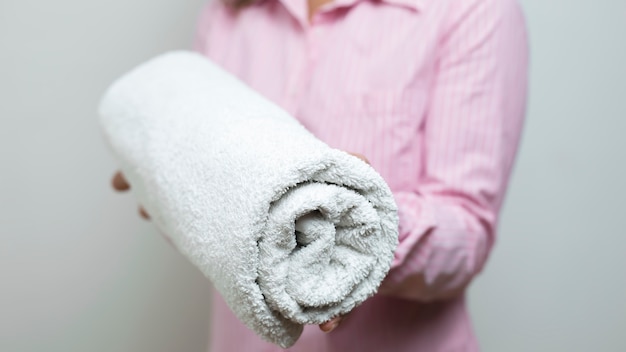 A woman is holding folded clean towels. 