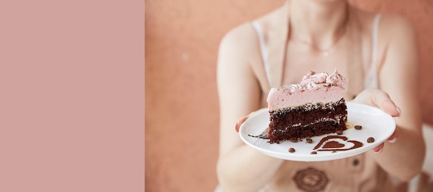 Woman is holding fruit chocolate piece of cake and cup of cappuccino on wooden table outside in the cafe terrace Atmospheric coffee time time for yourself Extra wide banner Copy space