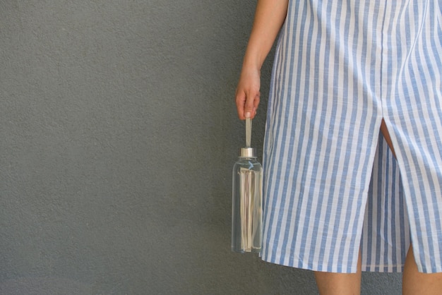 Woman is holding glass bottle with clear water