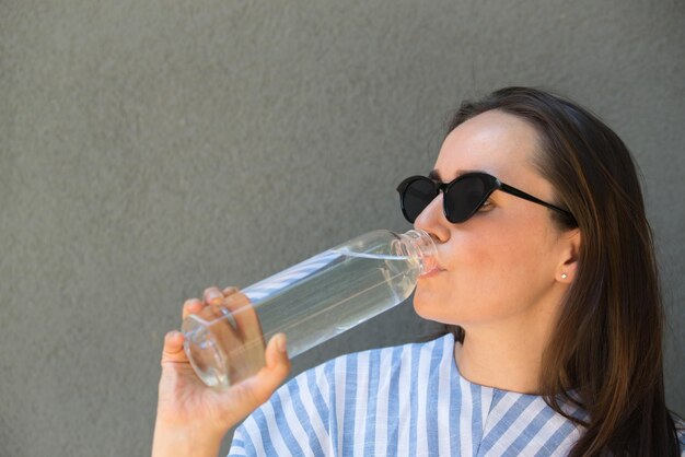 女性は澄んだ水でガラス瓶を保持しています