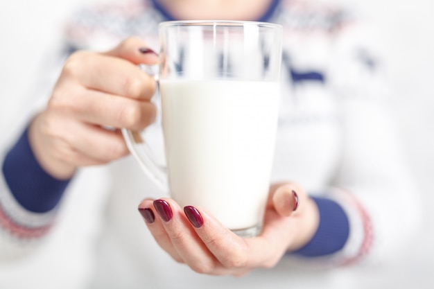 The woman is holding a glass mug of milk