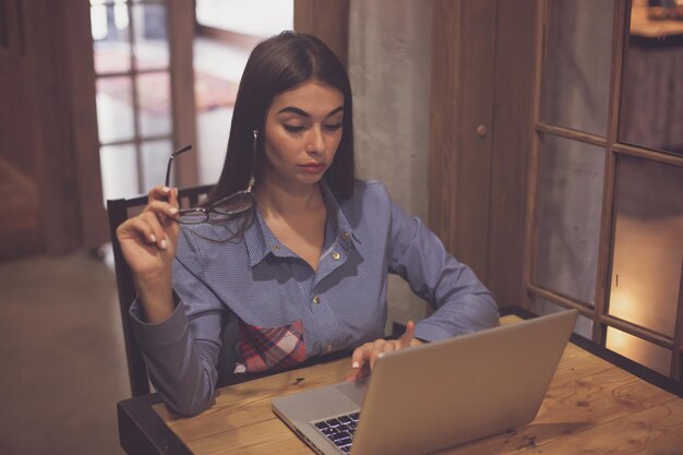 Woman is holding glasses in a hand and working