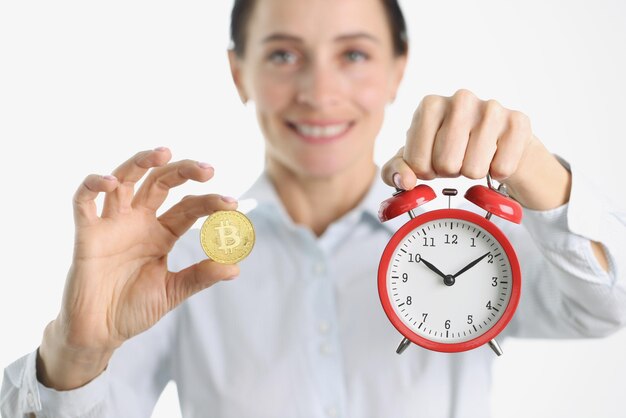 Woman is holding golden bitcoin and alarm clock cryptocurrency management concept