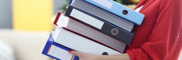 Woman is holding heavy stack of folders with documents. Women in business concept