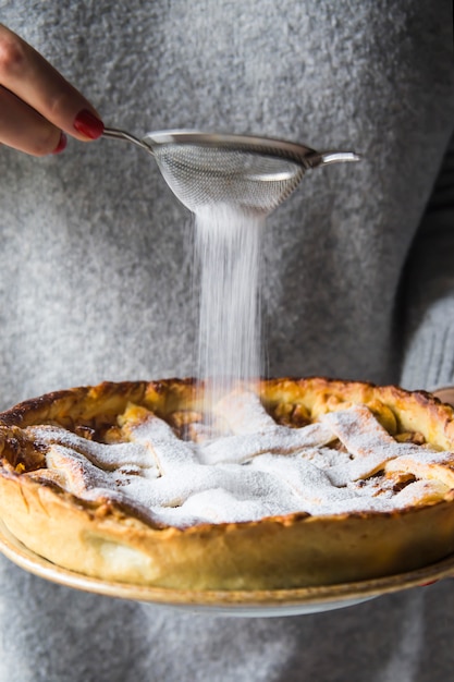 The woman is holding a homemade apple pie in her hands