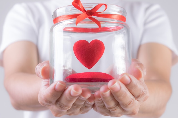 Foto la donna tiene in mano un barattolo con dentro un cuore rosso