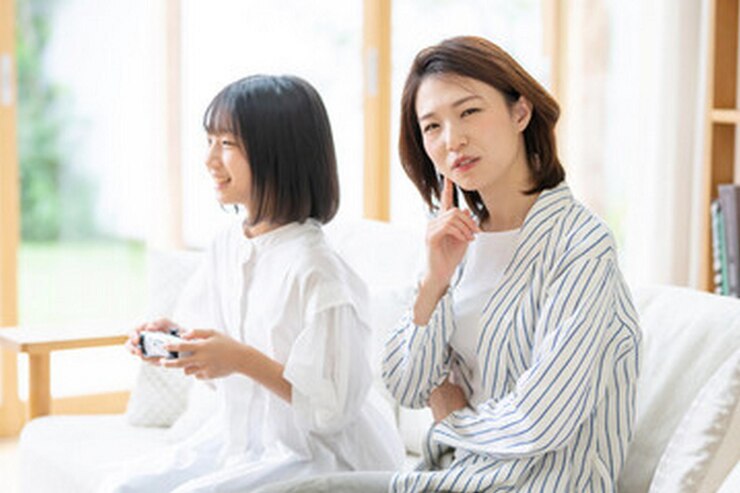 Photo 한 여성이 리모컨을 들고 있고 한 여성이 소파에 앉아 있습니다.