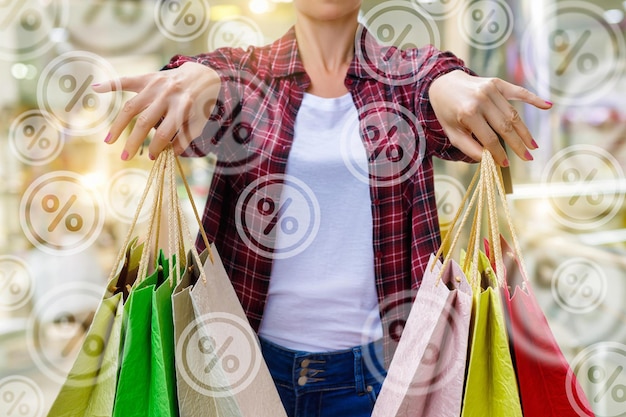 Foto una donna tiene in mano borse della spesa con la parola percentuale sul fondo.