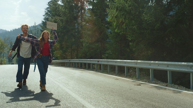 A woman is holding a sign that says " stop " on the side of a road.