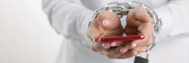 Woman is holding smartphone with her hands tied with chain addiction to phone and social