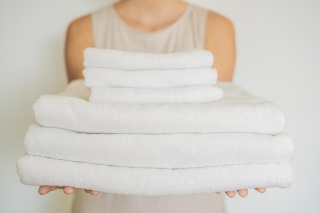 A woman is holding a stack of white towels Concept of service in hotels laundry spa