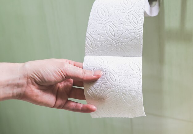 Woman is holding toilet paper in her hand.