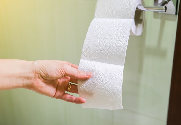 Woman is holding toilet paper in her hand.