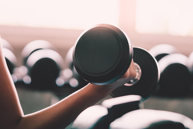 Фото Женщина держит вес, чтобы тренировать мышцы рук и плеч в фитнес-зале