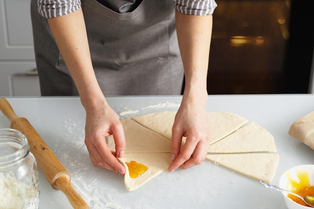 Photo a woman is in the kitchen baking bagels with jam. sweet pastry with your own hands.