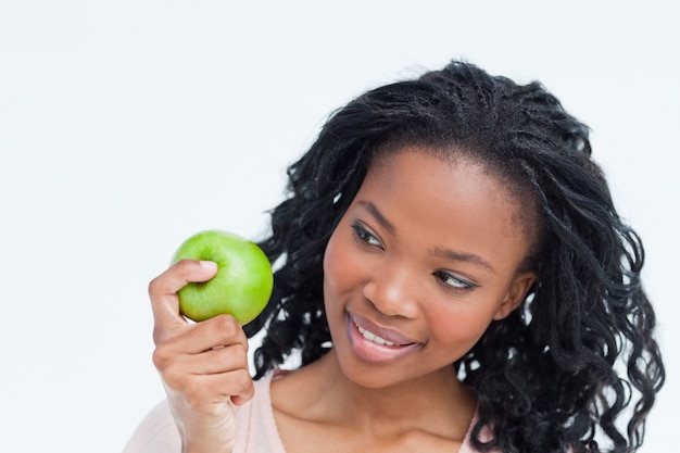 A woman is looking at an apple she is holding