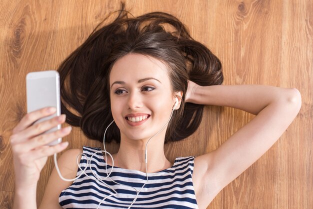 Woman is lying on the floor and listening music.