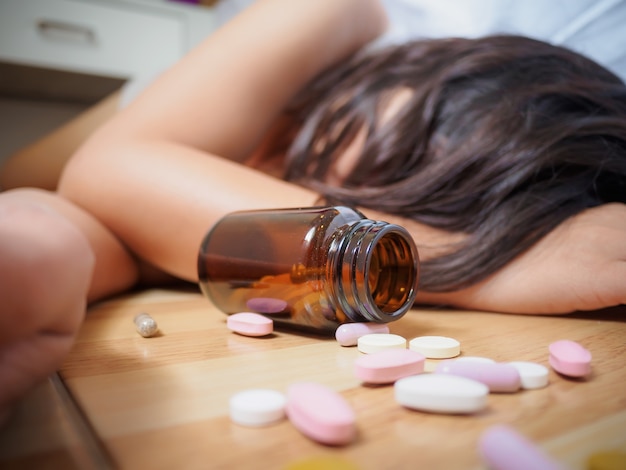 La donna è sdraiata sul pavimento con un sacco di pillole. sovradosaggio e concetto di suicidio.