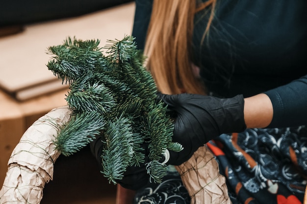 女性はクリスマスリースを作っています。