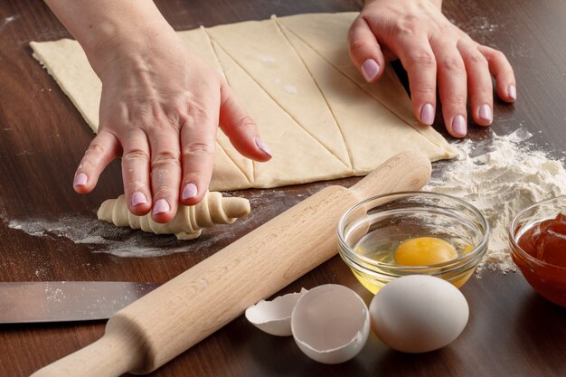 女性はキッチンでクロワッサンを作っています